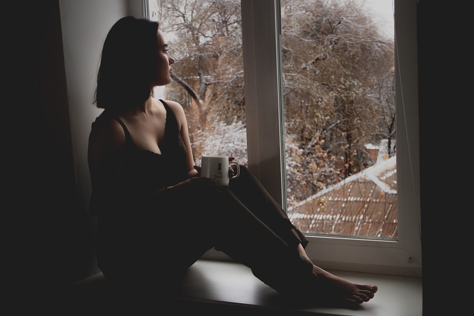 Smutná žena sedící u okna
